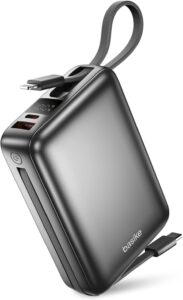 Carregador portátil Basike B201 preto de 20000mAh exibindo seus cabos embutidos na parte traseira e o pequeno display digital aceso.