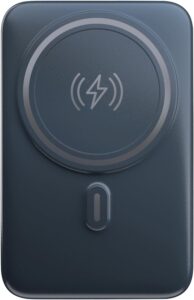 Powerbank Geonav MagSafe prateado acoplado magneticamente na traseira de um iPhone, apoiado na mesa através de seu suporte dobrável.