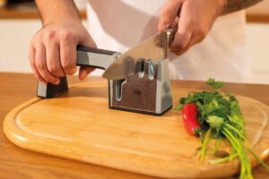 Afiador de facas manual Mor compacto na cor preta com detalhes em aço inox, exibindo as duas fendas de afiação e base antiderrapante.