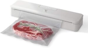Seladora a vácuo portátil Electrolux na cor branca sobre a mesa, selando hermeticamente um saco plástico com pedaços de carne vermelha.