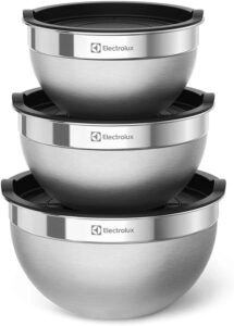 Conjunto de três tigelas bowls de aço inoxidável da Electrolux em tamanhos diferentes, com tampas plásticas brancas encaixadas ao lado.